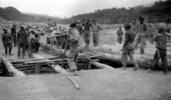 Les lourds troncs d' arbres nécéssaire à la consolidation de ce pont ( à moins qu'il ne s' agisse de la construction d'un abri enterré ?) sont ingénieusement déplacés à la seule force des Parachutistes Laotiens